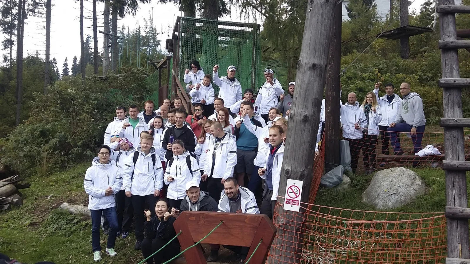 Účastníci teambuildingu v bielych tričkách pri spoločnej fotografii vonku