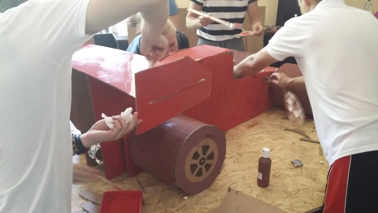 Účastníci zostavujú červený model vozidla na pracovnom stole