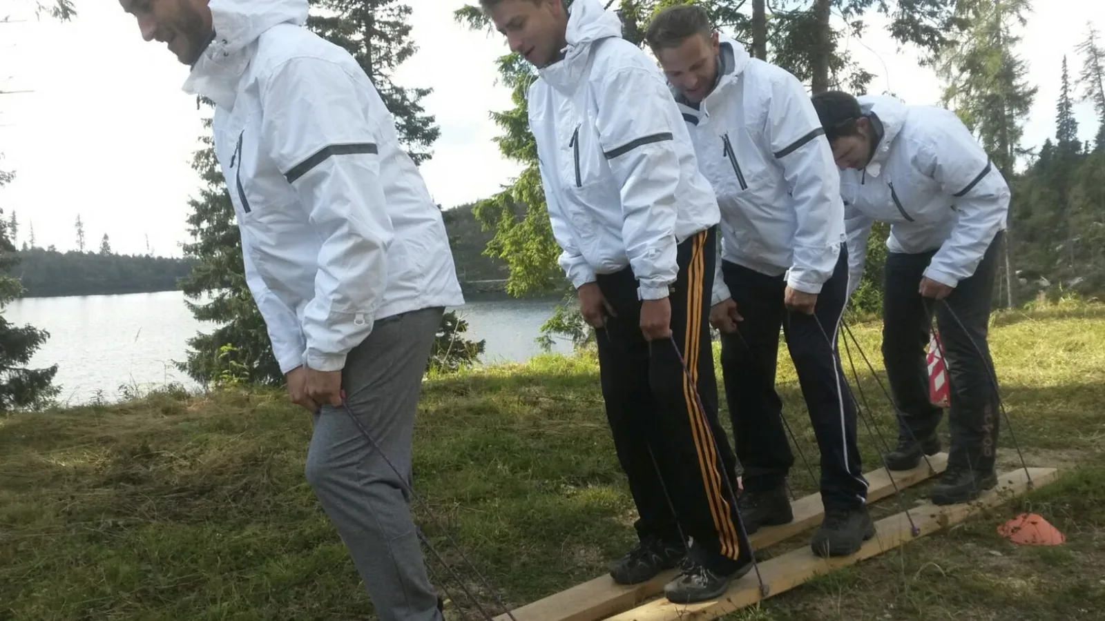 Účastníci skúšajú zosúladiť pohyb na spoločných drevených lyžiach
